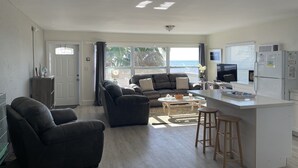 A modern living space with a kitchen, seating area, and large windows overlooking a scenic view.