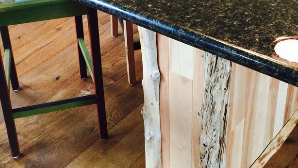 Eine Küche mit Granit Arbeitsplatte, Holzstühlen und Holzboden.