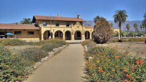 Ein Gebäude mit einem zentralen Innenhof, Rundbogenportalen und einem Weg, der dorthin führt.