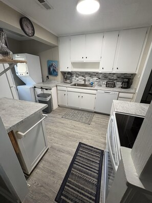 A modern kitchen with white cabinets, a built-in oven, a microwave, and a coffee maker.