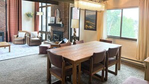 Un salon chaleureux avec une cheminée, une table à manger en bois et des sièges confortables.