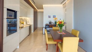 Een moderne keuken met een centraal eiland, een eethoek met gele stoelen, en een bloevas op de tafel.