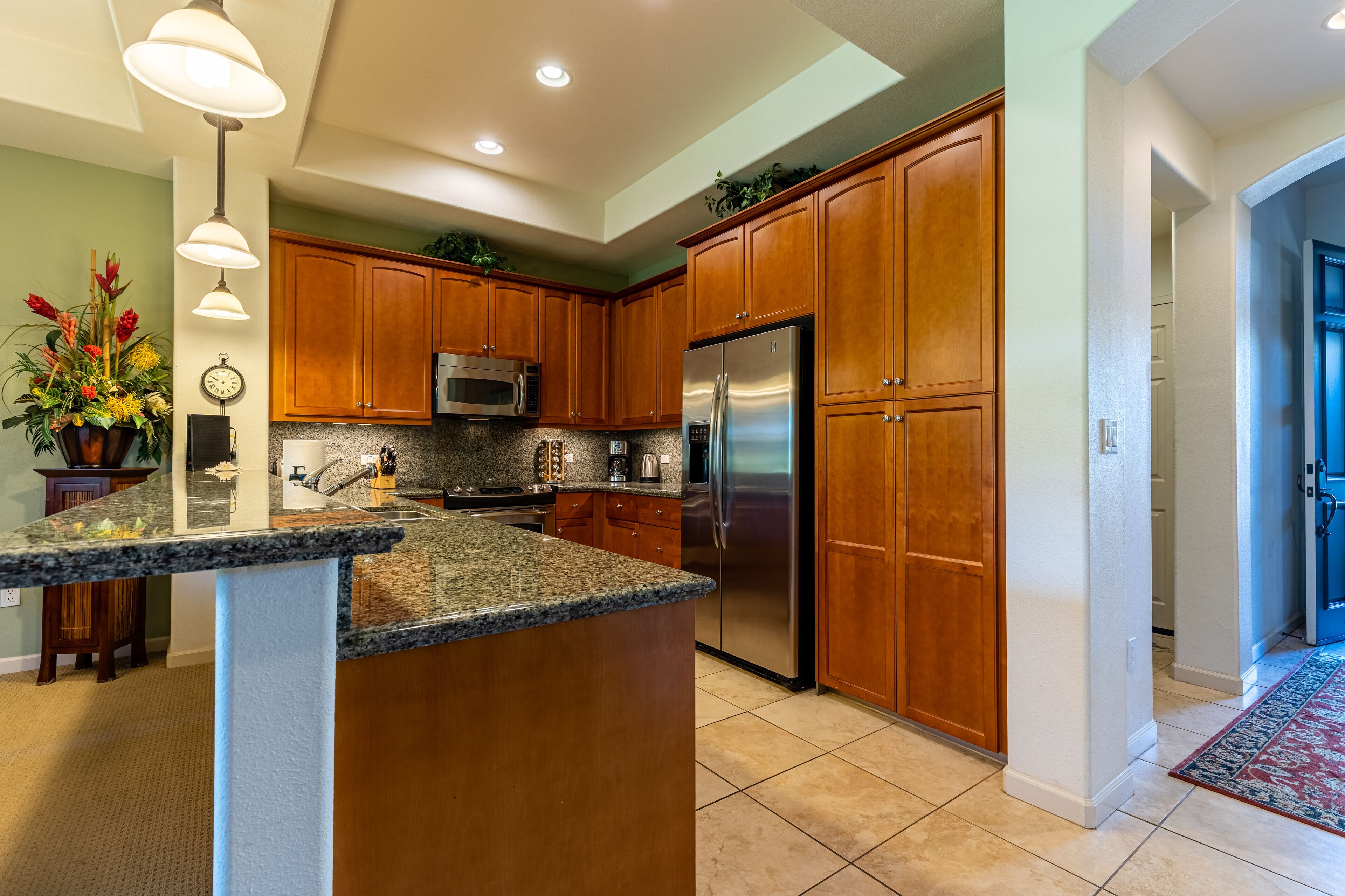 A kitchen with granite countertops, wooden cabinets, stainless steel appliances, and a built-in microwave.