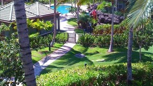 Un complexe hôtelier doté d’une piscine, de palmiers et d’un sentier menant à un bâtiment.