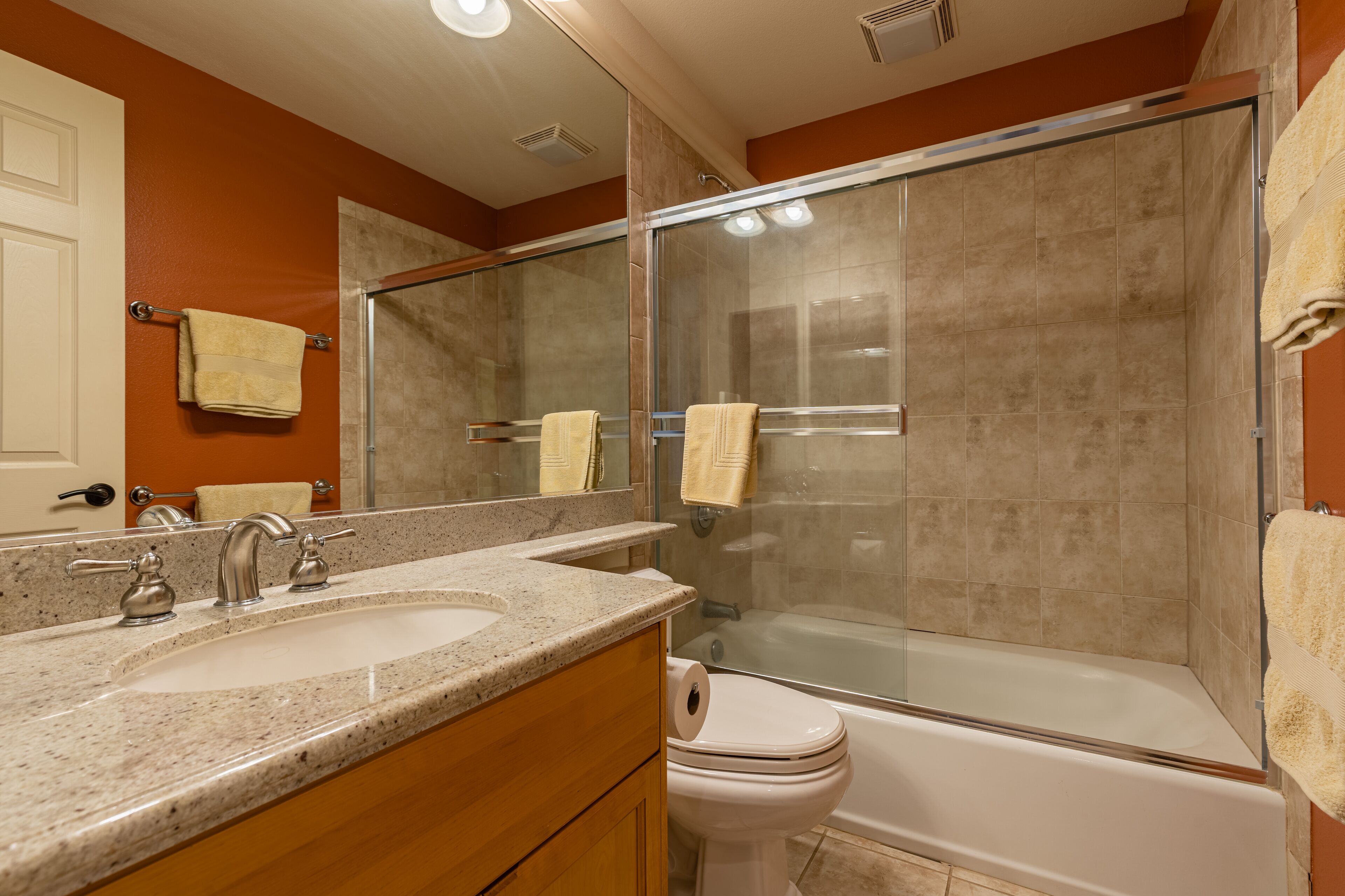 A bathroom with two sinks, a toilet, and a glass-enclosed shower.