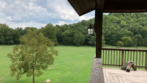 Una terraza de madera con vistas a un campo cubierto de hierba y un bosque denso.