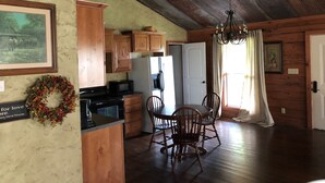 Una cocina rústica con armarios de madera, un refrigerador y un comedor con mesa y sillas.