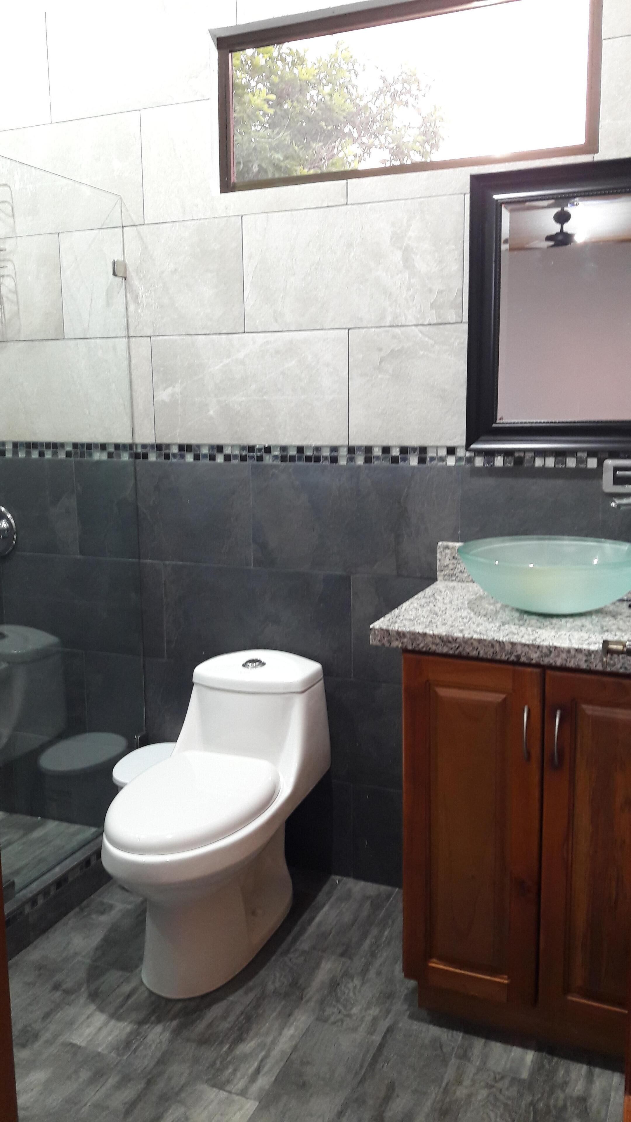 A bathroom with a toilet, a sink, and a window.