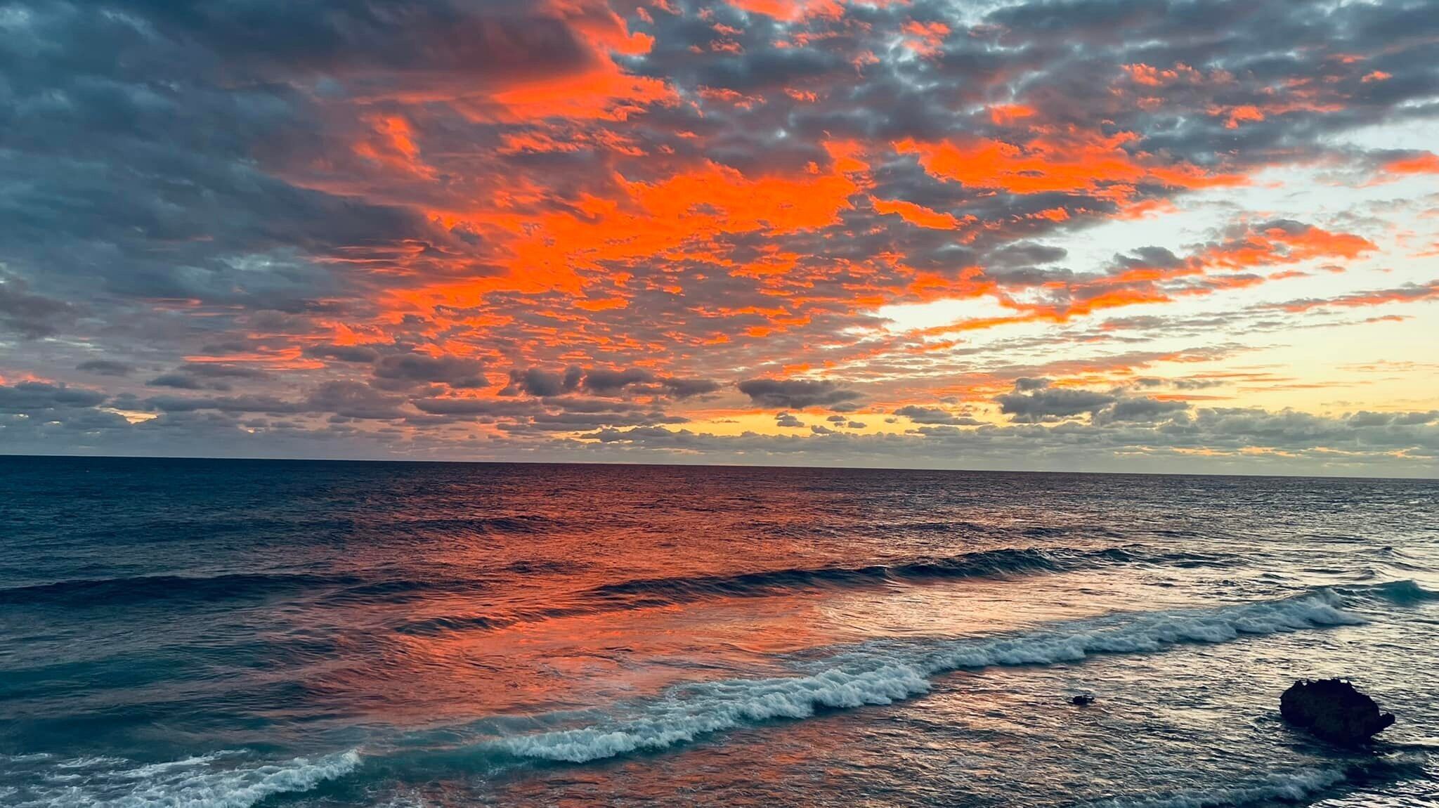 Un atardecer sobre el océano con olas rompiendo en la orilla.