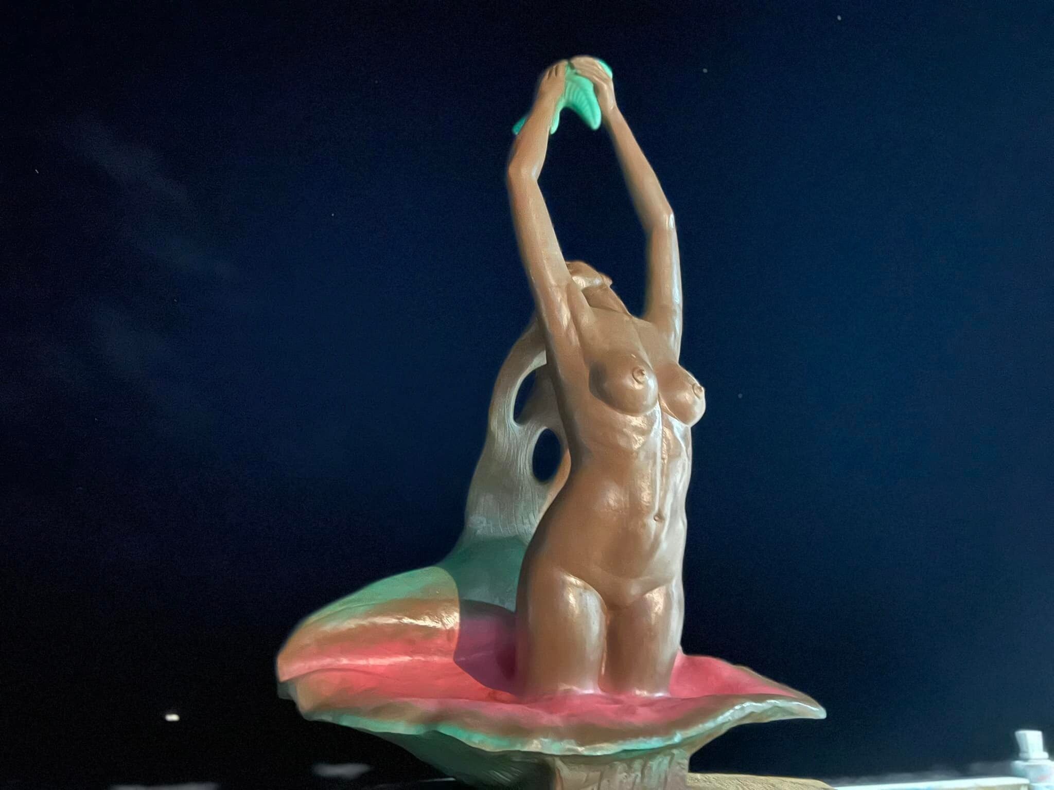 En skulptur af en kvinde i en dynamisk positur på en piedestal.