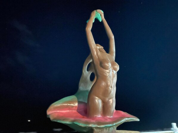Une sculpture représentant une femme dans une pose dynamique, placée sur un piédestal.