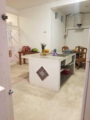 Compact kitchen with a central island featuring a decorative tile design, sink, microwave, water dispenser, and dining area with two chairs.
