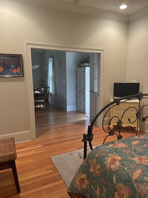 Une chambre à coucher avec un lit, une télévision, une commode et, au fond, un coin repas.