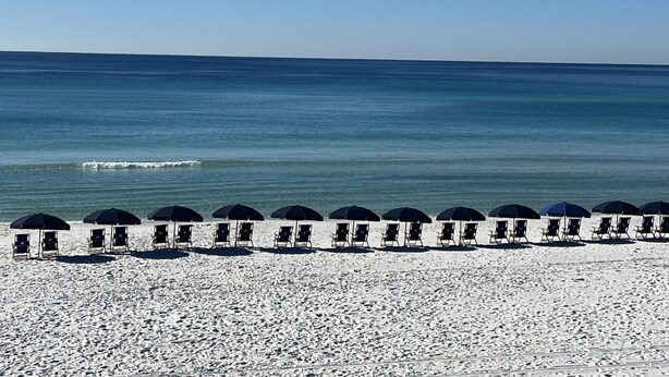 A beach with rows of sun umbrellas and lounge chairs facing the ocean. - RELAX, RENEW, REJUVENATE! (Santa Rosa Beach)