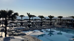 A poolside area with sun loungers, umbrellas, and palm trees. - RELAX, RENEW, REJUVENATE! (Santa Rosa Beach)