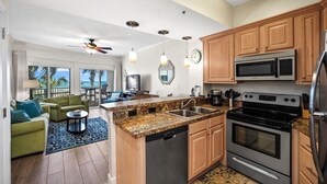 A modern kitchen with granite countertops, stainless steel appliances, and wooden cabinets. - Spacious 1BR/1.5BA Beach Condo/Low-Density Complex: Booking for Spring & Summer (Orange Beach)