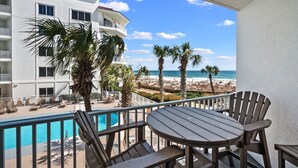 A balcony with a pool, chairs, and a view of the beach and ocean. - Spacious 1BR/1.5BA Beach Condo/Low-Density Complex: Booking for Spring & Summer (Orange Beach)