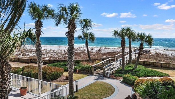 A beachfront property with a wooden deck, palm trees, and a view of the ocean. - Spacious 1BR/1.5BA Beach Condo/Low-Density Complex: Booking for Spring & Summer (Orange Beach)