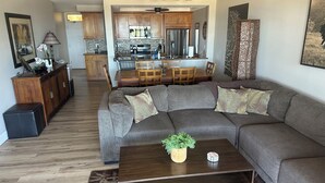 Una sala de estar moderna con un sofá modular, una mesa de centro con una planta y una zona de comedor con muebles de madera.