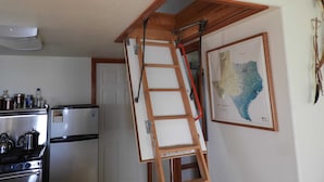 Eine Küche mit Kühlschrank, Herd und einer Holzleiter.