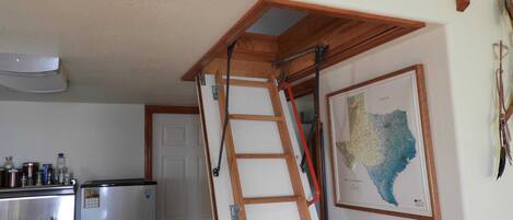 Una cocina con refrigerador, estufa y una escalera de madera.
