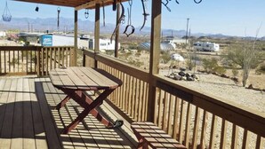 Eine Holzterrasse mit Picknicktisch und hängenden Ringen an der Decke.