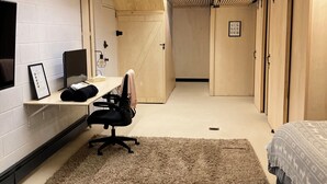 Une chambre moderne avec un plafond en lambris de bois, un bureau avec une chaise, un lit avec une literie à motifs et un tapis moelleux.