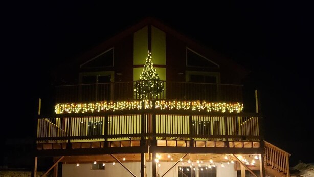 Un bâtiment à deux étages doté d’un balcon, d’un sapin de Noël et de guirlandes lumineuses.