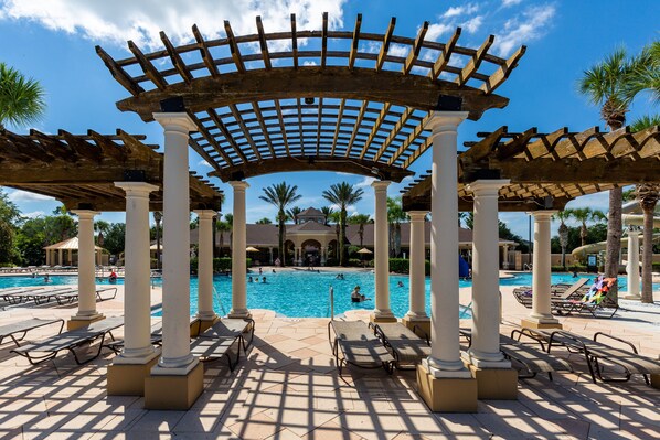 Relax by the pool surrounded by lounge chairs and umbrellas under a classic pergola.
