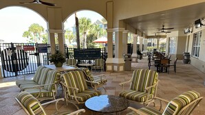 An outdoor patio area with striped wicker furniture, a round table, and a view of the market place. - 2 bed Windsor Hills Condo! Close to Disney World!  (Kissimmee)