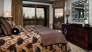 Une chambre avec un grand lit, une commode, un miroir et une vue sur le balcon.