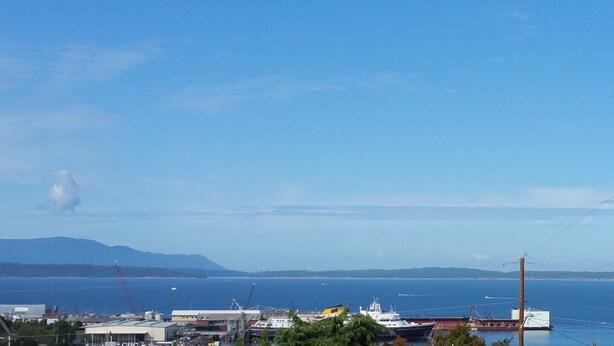A coastal view with a marina, boats, and industrial buildings. - CLASSY, MODERN FAIRHAVEN CONDO WITH GARAGE & EVSE. JUST STEPS TO EVERYTHING! (Bellingham)