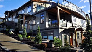 A modern two-story house with a balcony, large windows, and a landscaped garden. - CLASSY, MODERN FAIRHAVEN CONDO WITH GARAGE & EVSE. JUST STEPS TO EVERYTHING! (Bellingham)