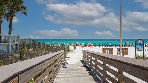 A wooden boardwalk leading to a beach with umbrellas and beach chairs. - Beachside Villas - lovely 2BR/2BA unit south of 30A, steps from the beach! (Seagrove Beach)