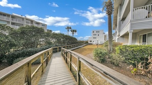 Stroll along the boardwalk to a charming residential area surrounded by lush greenery and modern buildings with balconies.