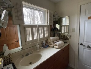 Une salle de bain avec une grande fenêtre, un lavabo, un miroir et des serviettes posées sur le comptoir.