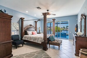 Un dormitorio amplio con cama con dosel, zona de estar y vistas al exterior.