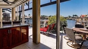 A spacious patio with a view of a marina, a wooden bar area, and outdoor seating.