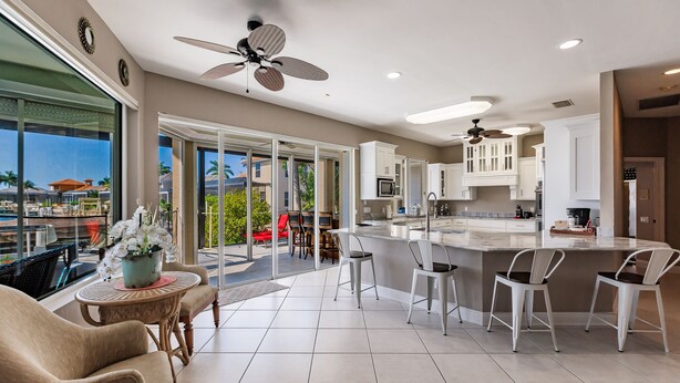 A spacious kitchen with white cabinets, a central island, and a dining area with chairs and a table.