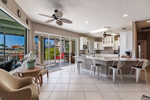 Una cocina amplia con armarios blancos, una isla central y un comedor con sillas y una mesa.