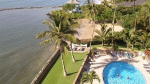 A resort with a swimming pool, palm trees, and a beach.