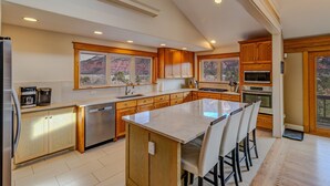 A modern kitchen with wooden cabinets, a large island, and a view of a mountainous landscape. - Mountain retreat, epic views, hot tub, decks, game room. A/C, Non-smoking. (Durango)
