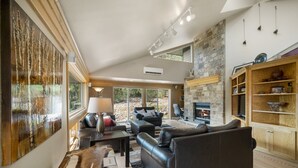 A spacious living room with a fireplace, leather sofas, and a stone wall. - Mountain retreat, epic views, hot tub, decks, game room. A/C, Non-smoking. (Durango)