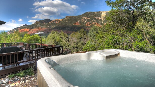 A hot tub with a mountainous backdrop, surrounded by a deck with outdoor seating. - Mountain retreat, epic views, hot tub, decks, game room. A/C, Non-smoking. (Durango)