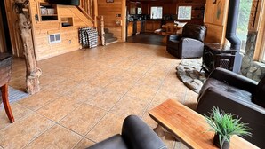 A wooden cabin interior with a living area, kitchen, and a stone fireplace. - Riverfront, with Hot Tub & Deck Overlooking the River! Sandy beach steps away! (Leavenworth)