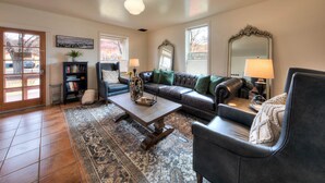 A living room with a sofa, armchairs, a coffee table, a bookshelf, and a large mirror. - The Main House (Cali Cochitta) (Moab)