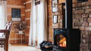 A cozy room with a fireplace, wooden walls, a dining table, and a chair. - Secluded Hilltop Sanctuary: Private Seasonal Pool, Hot Tub & Woodland Trail. (Trion)