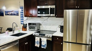 A modern kitchen with dark wooden cabinets, stainless steel appliances, a double oven, and a refrigerator.