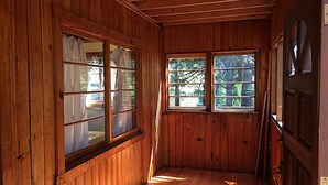 A wooden interior with a sloped ceiling, wooden walls, and a window with a view of trees.