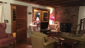 A cozy living room with a fireplace, wooden floors, and a television.